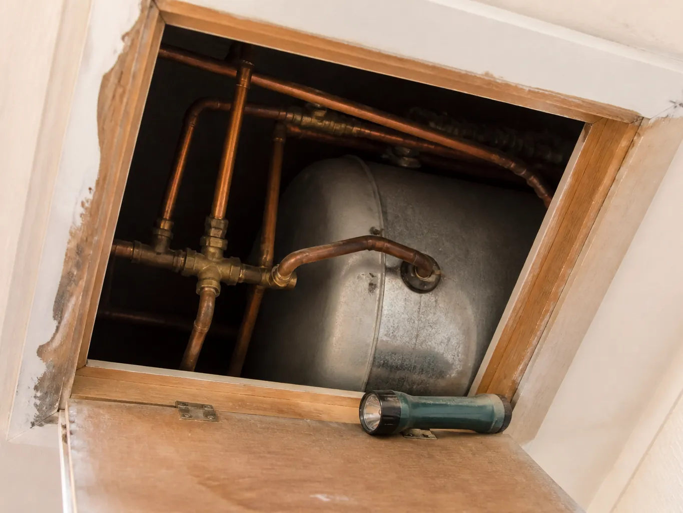 A domestic geyser and pipework in a ceiling recess
